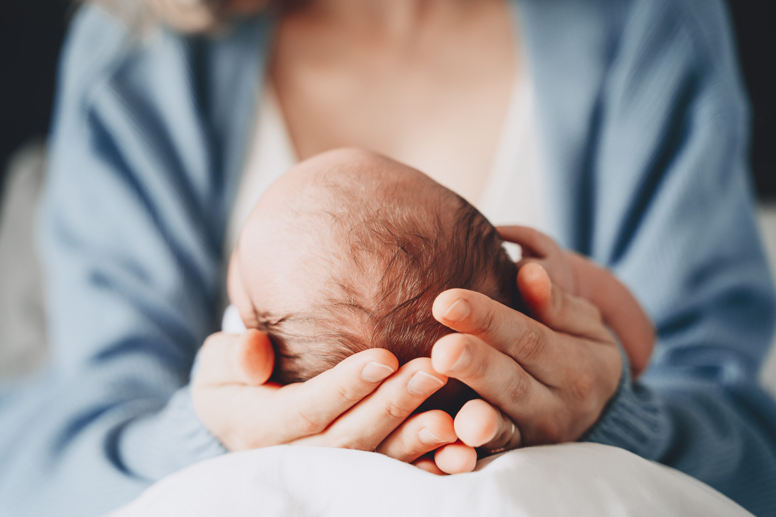 A Newborn is nested in its mother's lab holding gently bab's head with both her hands. Postpartum Doula Service includes Baby and mom care, and sometimes any chores that gives mother and baby time to themselves.